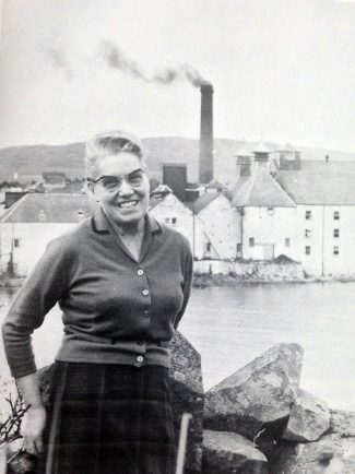 Bessie Williamson poses in front of the Laphroaig distillery. Image courtesy of Laphroaig. 